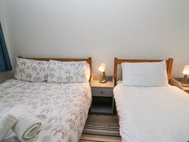 A bedroom with one double bed and one single bed with lamps on nightstands at 14 Coedrath Park in Saundersfoot