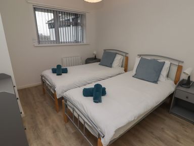 A bedroom with two single beds and bedside tables at 19 Coedrath Park in Saundersfoot