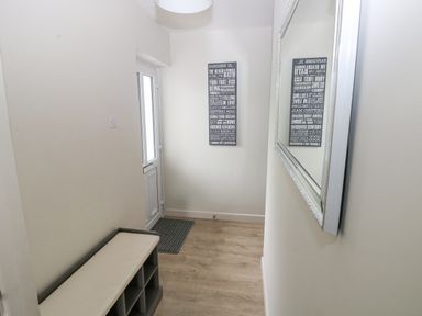 A small entryway with a bench and storage cubbies a wall mirror and a decorative wall sign at 29 Coedrath Park Saundersfoot