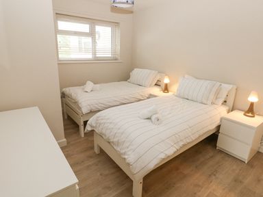 A bedroom with two single beds side by side with striped bedding and rolled towels on each bed at 29 Coedrath Park in Saundersfoot