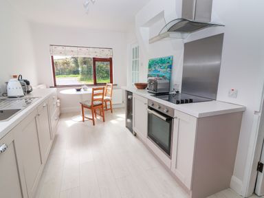 A kitchen with a dining area table two chairs an oven stovetop toaster kettle and a window at Tonakilla House in Tonakilly near Camp County Kerry