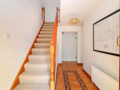 A hallway with tiled floor and carpeted stairs with wooden railing and a map on the wall at Tonakilla House in Tonakilly near Camp County Kerry