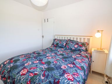 A bedroom with a double bed with floral bedding and a bedside table with a lamp at Tonakilla House in Tonakilly near Camp County Kerry