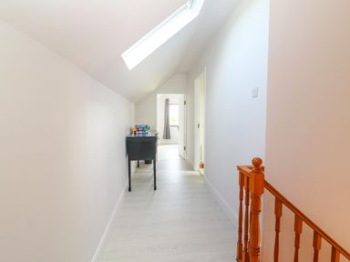 A hallway with light wood flooring a black table with board games on top a skylight and wooden stair railing at Tonakilla House in Tonakilly near Camp County Kerry