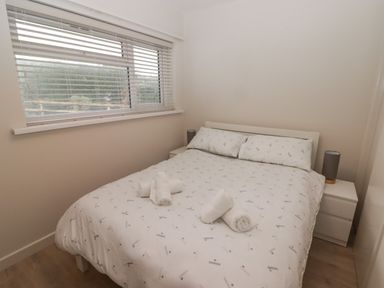 A bedroom with a double bed and two bedside tables with lamps at 23 Coedrath Park Saundersfoot