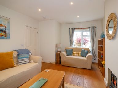 A living room with two sofas a wooden coffee table a lamp a bookshelf and a window at Sea Breeze in Swanage