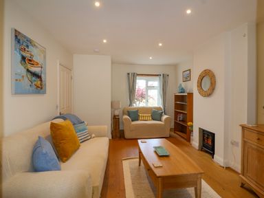 A living room with two sofas a wooden coffee table a bookcase and a small fireplace at Sea Breeze in Swanage