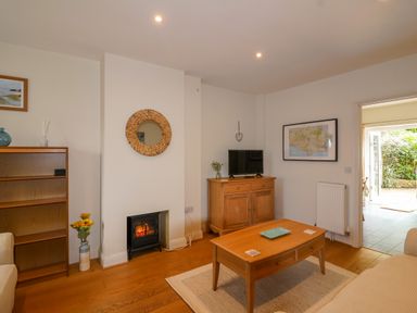 A living room with a coffee table a small fireplace wooden furniture and a television at Sea Breeze in Swanage