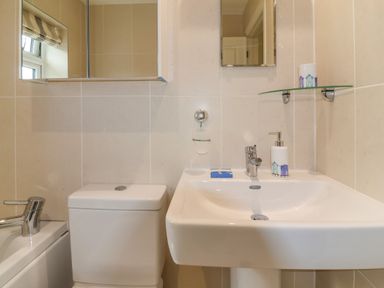 A bathroom with a toilet sink bathtub and two mirrors at Sea Breeze in Swanage