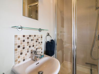 A bathroom with a sink towel ring and a glass door shower at Sea Breeze in Swanage