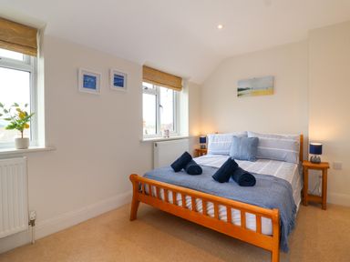 A bedroom with a wooden bed frame and blue bedding at Sea Breeze in Swanage