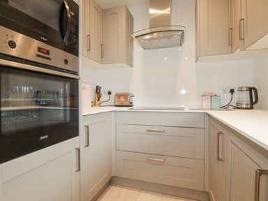 A kitchen with built in oven microwave toaster kettle and cabinets at Rainbow Lodge in St Tudy