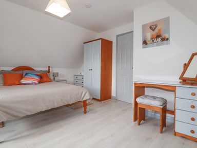 A bedroom with a bed a wardrobe a dressing table and a stool at Rainbow Lodge in St Tudy
