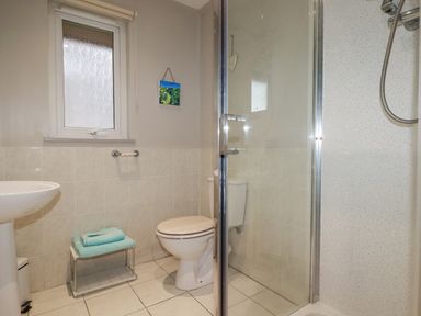 A bathroom with a shower enclosure toilet sink and a window at Rainbow Lodge in St Tudy