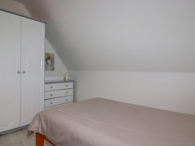 A bedroom with a bed a wardrobe and a chest of drawers at Rainbow Lodge in St Tudy