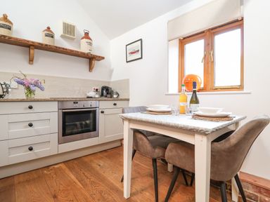 A kitchen with a dining table set for two and kitchen cabinets at The Nook in Chediston near Halesworth