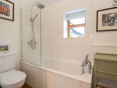 A bathroom with a bathtub shower combination toilet window and framed pictures at The Nook in Chediston near Halesworth