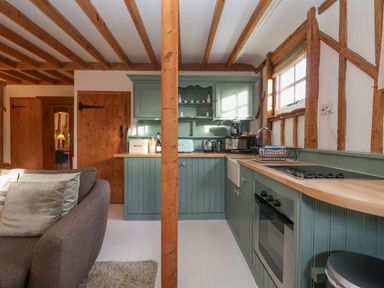 A kitchen with green cabinets wooden countertops and exposed wooden beams at Twosome in Chediston near Halesworth