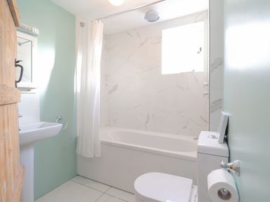 A bathroom with a bathtub shower combination toilet and sink at Twosome in Chediston near Halesworth