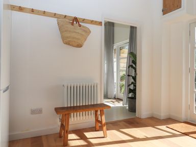 A hallway with a wooden bench and coat rack with a bag hanging at The Apple Shed in Upexe near Silverton