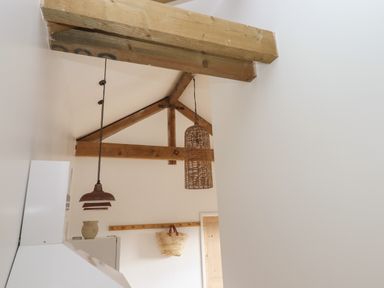 A ceiling with wooden beams and two hanging lamps above the kitchen at The Apple Shed in Upexe near Silverton
