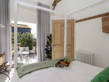 A bedroom with a four-poster bed and breakfast tray next to a door opening onto an outdoor patio at The Apple Shed in Upexe near Silverton