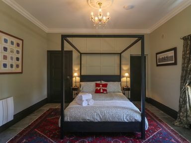 A bedroom with a four-poster bed two bedside tables with lamps and rolled towels on the bed at Bohan Bo Tinteskin near Kilmuckridge County Wexford