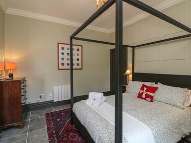 A bedroom with a four poster bed dresser lamps and framed pictures at Bohan Bo in Tinteskin near Kilmuckridge County Wexford