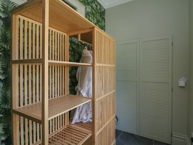 A wooden shelving unit with two white bathrobes hanging and a closed louvered door in the corner of the room at Bohan Bo in Tinteskin near Kilmuckridge County Wexford