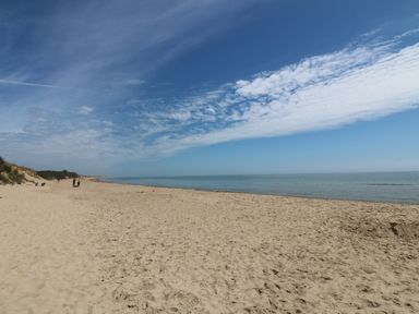 A sandy beach with people in the distance under a blue sky with clouds at Bohan Bo in Tinteskin near Kilmuckridge County Wexford
