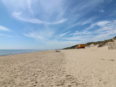 A sandy beach with a few people a lifeguard hut and dunes with fences at Bohan Bo in Tinteskin near Kilmuckridge County Wexford