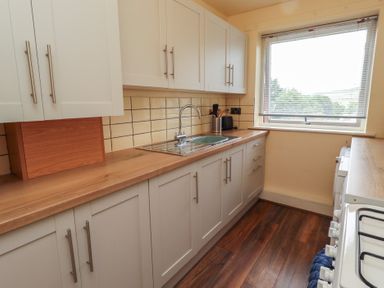 A kitchen with cabinets and sink at Flodden Apartment in Wooler