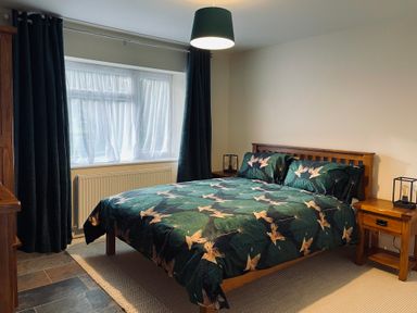 A bedroom with a wooden bed and matching bedside tables with lamps at Harvest Moon Cottage in Much Cowarne
