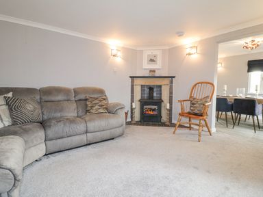 A living room with a gray couch a wooden chair and a fireplace at The Lodge at Wildersley Farm in Belper