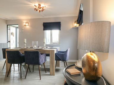 A dining room with a wooden table and blue chairs beside a lamp on a side table at The Lodge at Wildersley Farm in Belper