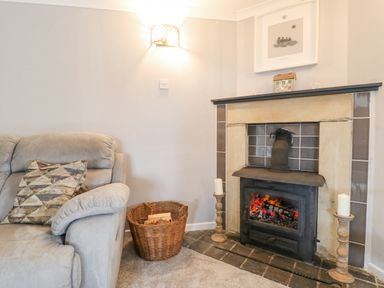 A living room with a sofa a fireplace and a basket of firewood at The Lodge at Wildersley Farm in Belper