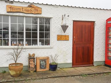 Exterior of a building with a wooden door and window with pots and signs near Tal Sarn Shepherd Hut in Dwyran near Niwbwrch Newborough