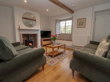 A living room with two sofas a coffee table and a fireplace at Blossom Cottage in Chipping Campden