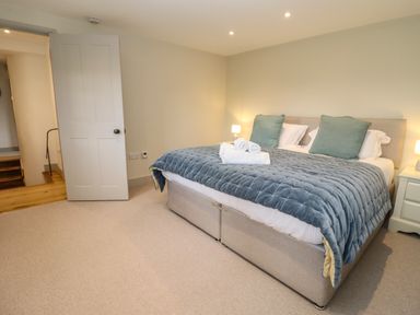 A bedroom with a large bed covered with a blue quilt and towels placed on top at Blossom Cottage in Chipping Campden