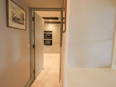A hallway with a door leading to a kitchen with built-in ovens at Green Yew Winster near Bowness-On-Windermere