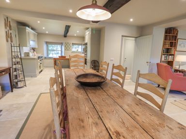 A kitchen and dining area with a wooden table and chairs and a metal bowl at Green Yew Winster near Bowness-On-Windermere