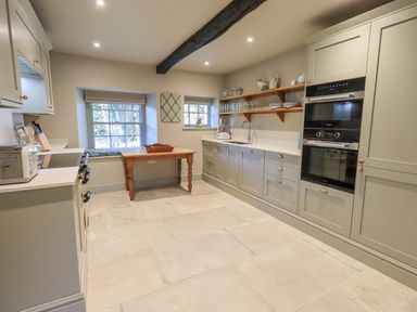 A kitchen with cabinets ovens and a wooden table at Green Yew in Winster near Bowness-On-Windermere