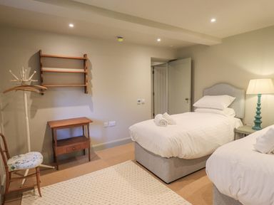 A bedroom with two single beds a wooden chair and a small wooden table at Green Yew Winster near Bowness-On-Windermere