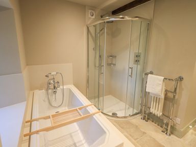 A bathroom with a bathtub, glass shower enclosure, and a towel rack at Green Yew Winster near Bowness-On-Windermere