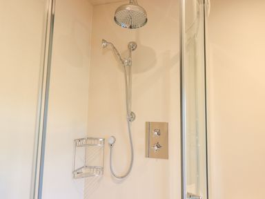 A shower area with a rain shower head handheld shower and control knobs at Green Yew in Winster near Bowness-On-Windermere
