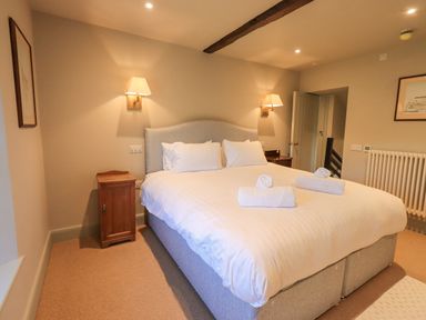 A bedroom with a double bed flanked by wall lamps and wooden bedside tables at Green Yew in Winster near Bowness-On-Windermere