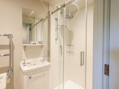 A bathroom with a glass shower enclosure a white sink with taps a mirror a towel rack and a soap bar at Green Yew Winster near Bowness-On-Windermere
