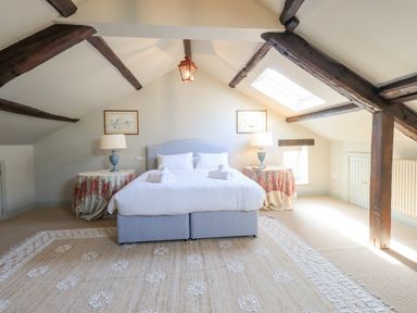 A bedroom with a bed two tables with lamps and exposed wooden beams at Green Yew in Winster near Bowness-On-Windermere