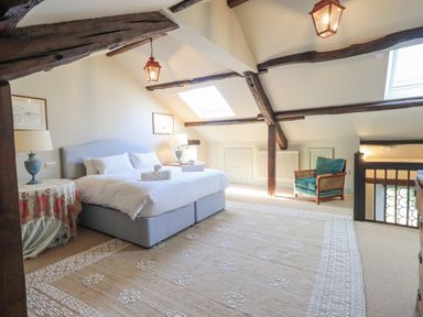 A bedroom with a double bed two lamps a chair exposed wooden beams and skylights at Green Yew in Winster near Bowness-On-Windermere