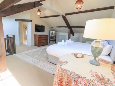 A bedroom with a bed and folded towels a dresser a mirror and a table with a lamp at Green Yew Winster near Bowness-On-Windermere